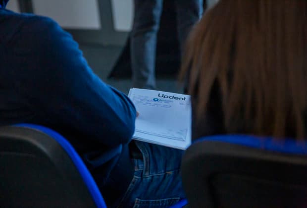 A participant takes notes during the Minimal Invasive Adhesive Dentistry Master Class, capturing key concepts on an Updent-branded notepad provided by Dentstore.