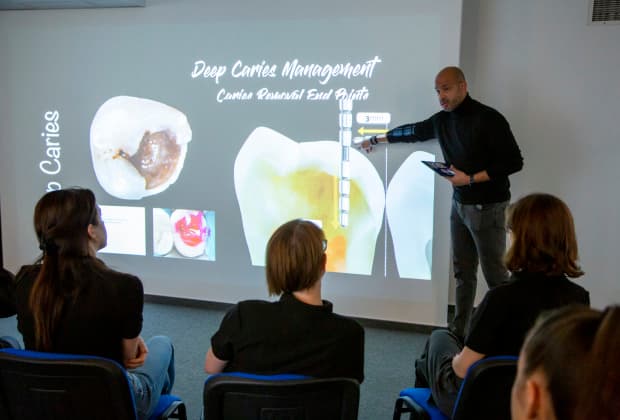 The instructor explains deep caries management techniques during the Master Class, using clinical visuals to illustrate precise caries removal endpoints and decision-making protocols.